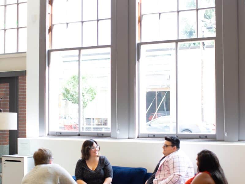 four persons sitting on chairs near window during daytime